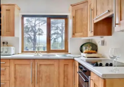 a kitchen with wooden cabinets and a sink and a window at Mountain View Cottage, Hot Tub , Stunning Views in Llanhamlach