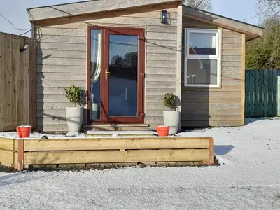 a tiny house with a door and two potted plants at The Hut B & B in Mochdre