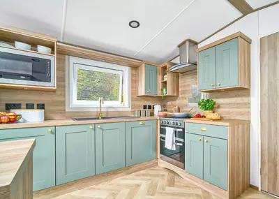 a kitchen with blue cabinets and a window at Ocean Heights Holiday Park in New Quay