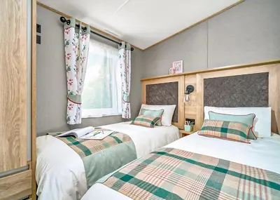 a bedroom with two beds and a window at Ocean Heights Holiday Park in New Quay