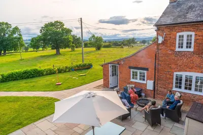 a group of people sitting on a patio with an umbrella at Marrington Farmhouse in Chirbury