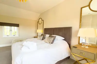a bedroom with a large white bed and a mirror at Marrington Farmhouse in Chirbury