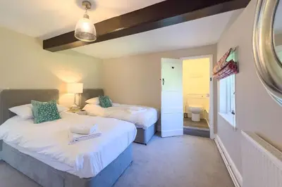 a bedroom with two beds and a bathroom at Marrington Farmhouse in Chirbury