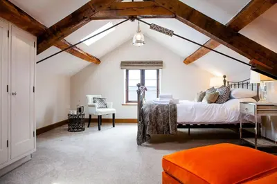 an attic bedroom with a bed and a chair at Camlad Barn in Chirbury