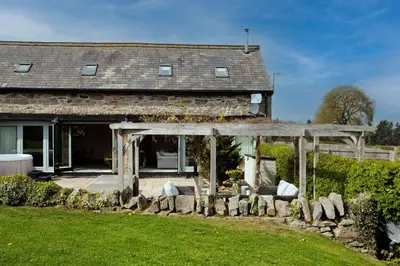 an old house with a stone fence in front of it at Camlad Barn in Chirbury