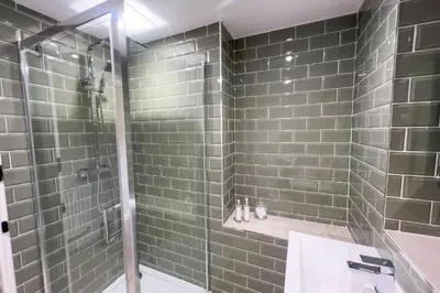 a bathroom with a shower with green tiles at Roundton Farmhouse in Chirbury