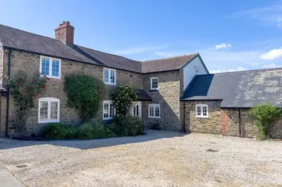 a large brick house with a driveway in front of it at Roundton Farmhouse in Chirbury
