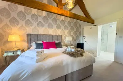 a bedroom with a large bed with a pink pillow at Roundton Farmhouse in Chirbury