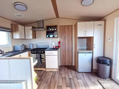 a kitchen with white cabinets and a counter top at Snowdonia Sunbeach Holiday Sea and Mountain view in Llwyngwril