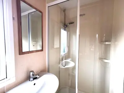 a bathroom with a sink and a shower with a mirror at Snowdonia Sunbeach Holiday Sea and Mountain view in Llwyngwril