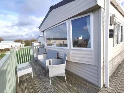 a porch with a couch and chairs on a deck at Snowdonia Sunbeach Holiday Sea and Mountain view in Llwyngwril