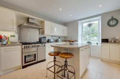 a kitchen with white cabinets and a counter with stools at 4 Bed in Brithdir oc-wag722 in Cross Foxes