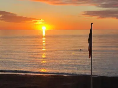 a flag on the beach with the sunset in the background at Stunning Aberystwyth South Beach Apartment in Aberystwyth