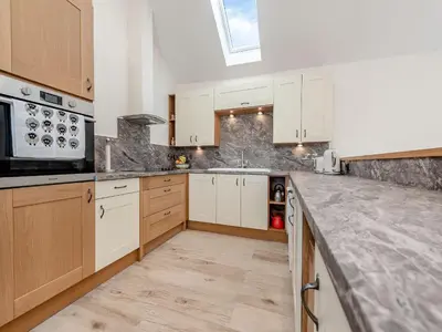 a kitchen with white cabinets and a counter top at Parlwr Godro - Uk41513 in Llanfair Clydogau