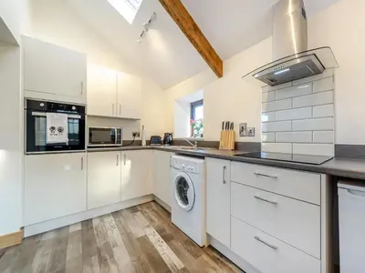 a kitchen with white cabinets and a washer and dryer at Ty Gwair - Uk41512 in Lampeter