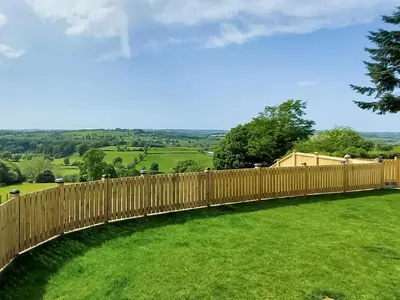 a wooden fence in a yard with a green field at Yr Hen Beudy in Tregaron