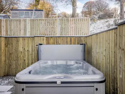 a hot tub in front of a wooden fence at Yr Hen Beudy in Tregaron