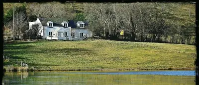 a house on a hill next to a body of water at Lake view Romantic retreat in Aberystwyth