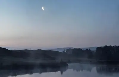 a misty lake with trees and mountains in the background at Lake view Romantic retreat in Aberystwyth