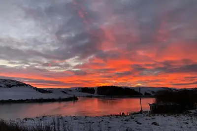 a sunset over a body of water with snow at Lake view Romantic retreat in Aberystwyth