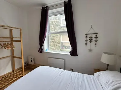 a bedroom with a white bed and a window at Flat 2, Ty Newydd in Barmouth