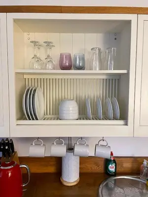a kitchen sink with plates and glasses on shelves at Flat 2, Ty Newydd in Barmouth