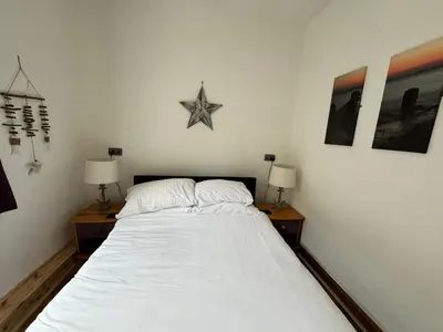 a bedroom with a large white bed with two nightstands and a star at Flat 2, Ty Newydd in Barmouth