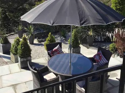 a table and chairs with an umbrella on a balcony at Tre Mynach Barmouth in Barmouth