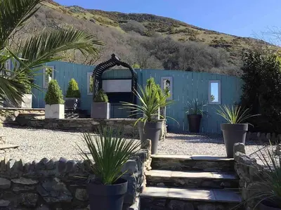 a blue building with plants in front of a mountain at Tre Mynach Barmouth in Barmouth