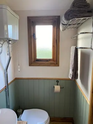 a bathroom with a toilet and a window at Silver Fern Glamping in Aberystwyth