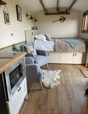 a living room with a couch and a bed at Silver Fern Glamping in Aberystwyth