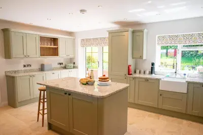 a large kitchen with white cabinets and a counter top at Country Crabtree Bungalow with large wild garden in Leighton