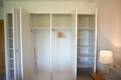 a closet with white shelves and a lamp at Country Crabtree Bungalow with large wild garden in Leighton
