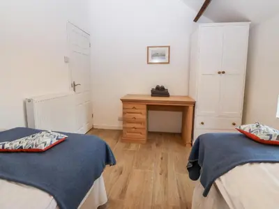 a bedroom with two beds and a wooden desk at Y Bwthyn in Dyffryn