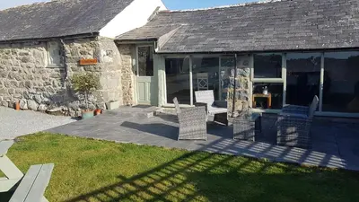 a stone house with chairs on a patio at Y Bwthyn in Dyffryn