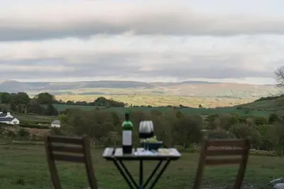 a table with a bottle of wine and two chairs at Dyffryn Ceri in Penuwch