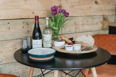 a table with wine bottles and bread and purple flowers at Dyffryn Ceri in Penuwch