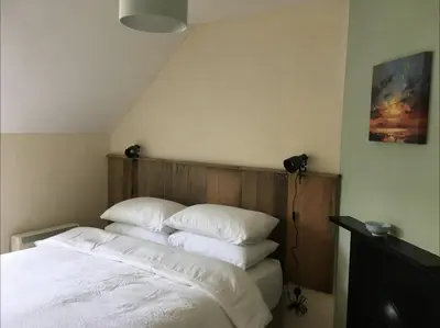 a bedroom with a bed with white sheets and pillows at Cosy Arts & Crafts Cottage with stunning views in Brecon