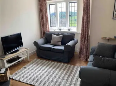 a living room with a couch and a television at Cosy Arts & Crafts Cottage with stunning views in Brecon