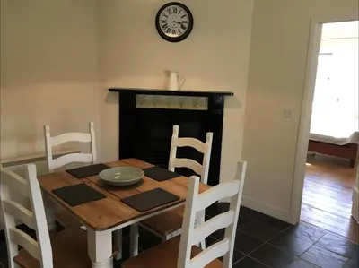 a dining room table and chairs with a clock on the wall at Cosy Arts & Crafts Cottage with stunning views in Brecon