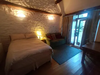 a bedroom with a bed and a chair and a window at Y Swdio, Ferm Glandwr in Barmouth