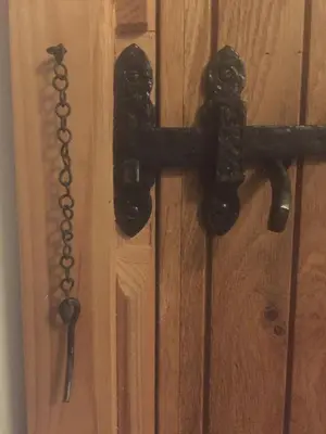 a black door knocker on a wooden door with a chain at Y Swdio, Ferm Glandwr in Barmouth