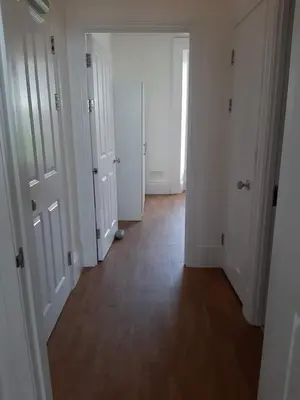 an empty hallway with white doors and a wooden floor at Beautiful Seafront 1 bedroomed apartment in Aberystwyth