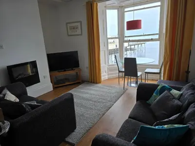 a living room with two couches and a large window at Beautiful Seafront 1 bedroomed apartment in Aberystwyth