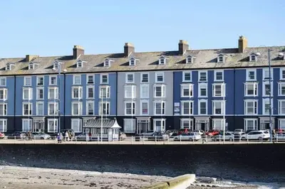 a large blue building next to a body of water at Beautiful Seafront 1 bedroomed apartment in Aberystwyth