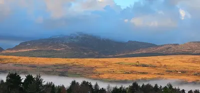 a mountain in the middle of a field with a lake at Log cabin - free parking garden & pet friendly in Trawsfynydd
