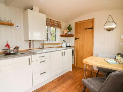 a kitchen with white cabinets and a wooden table at Marches Way in Rhayader