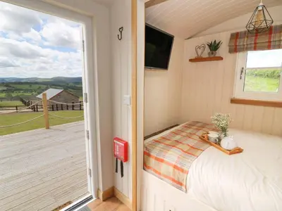 a bedroom with a bed and a balcony at Marches Way in Rhayader