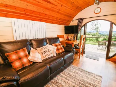 a leather couch in a living room with a table at Meadow View in Rhayader