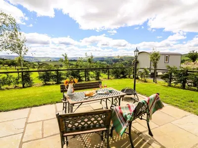 a patio with a table and chairs and a view of a field at Meadow View in Rhayader
